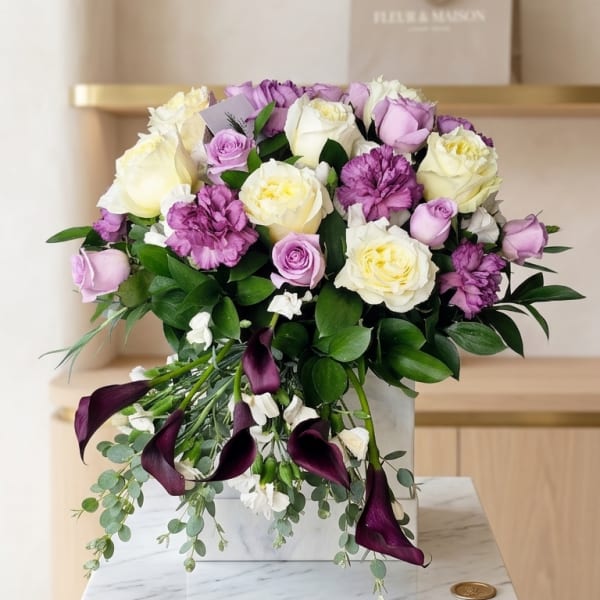 Bouquet of cream and lavender roses with purple calla lilies in a white box