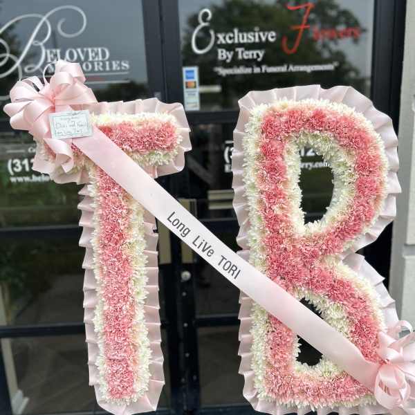 Pink and white floral funeral tribute in the shape of the number 18 with a ribbon