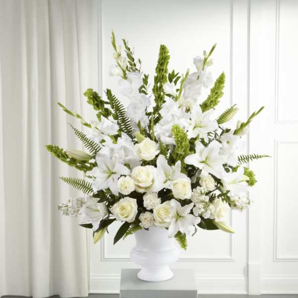 White floral arrangement in a white urn vase