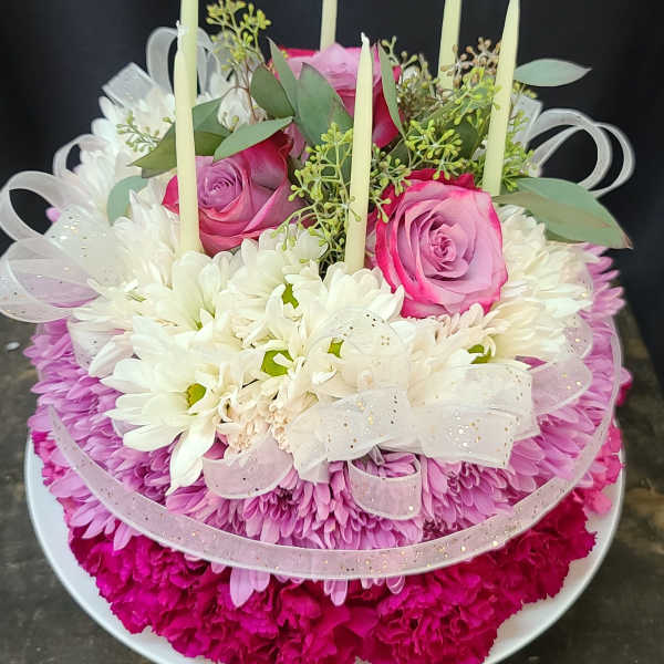 Round floral arrangement with pink roses, white daisies, and tall candles