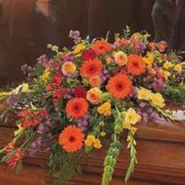 Large colorful floral spray on a wooden casket