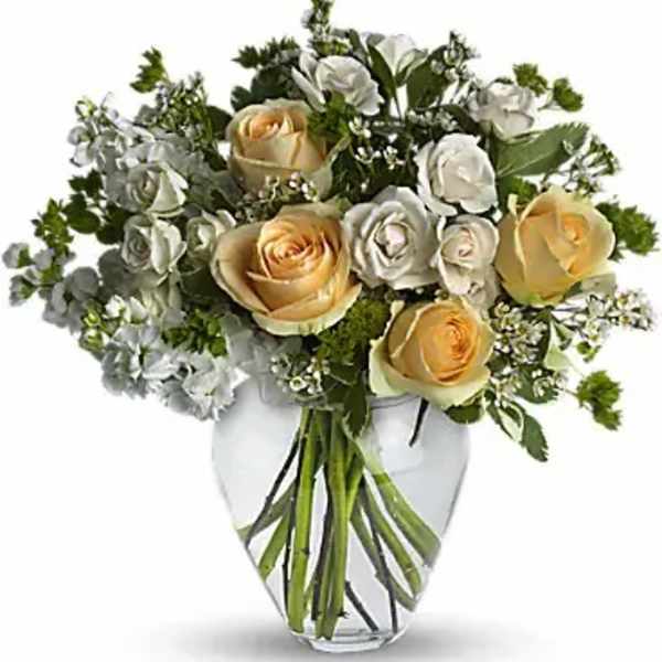 Bouquet of cream and pale yellow roses in a clear glass vase