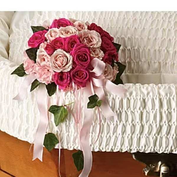 Pink and white rose bouquet with trailing ribbon on a casket