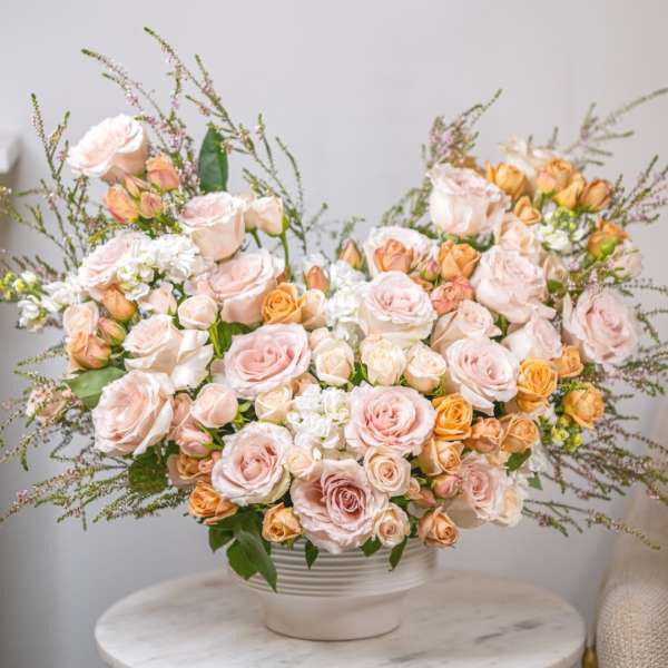 Large bouquet of pale pink and peach roses in a white vase