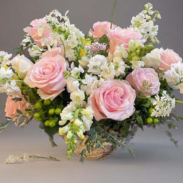 Pink roses and white flowers arranged in a low vase