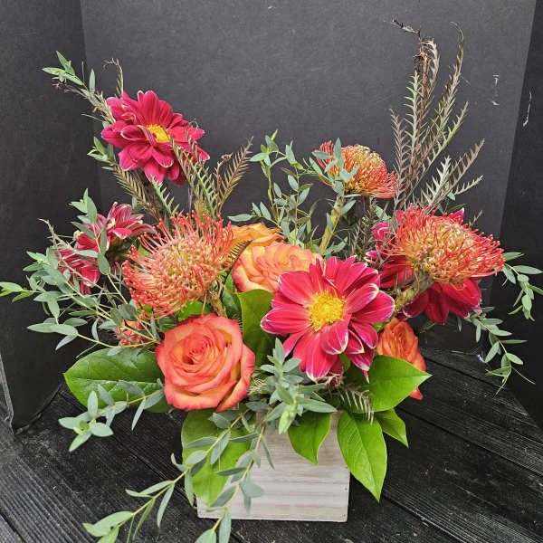 Bright pink and orange flowers arranged in a white wooden box