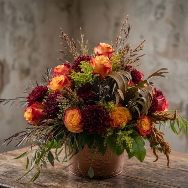 Orange and burgundy roses arranged in a low decorative pot