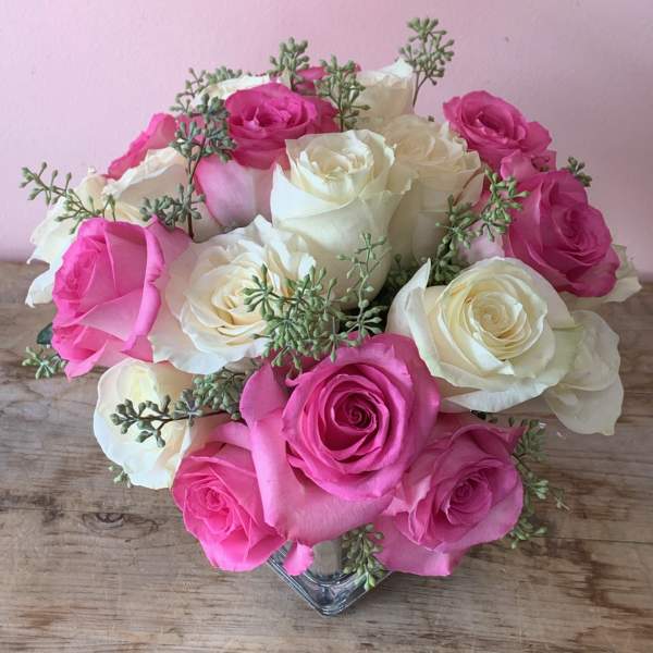 Pink and white roses arranged in a clear glass vase