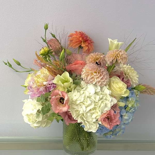 Pastel mixed flower arrangement in a textured glass vase