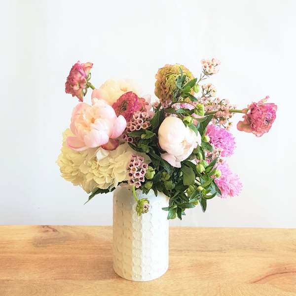 Pastel floral arrangement in a white vase with pink and cream blooms