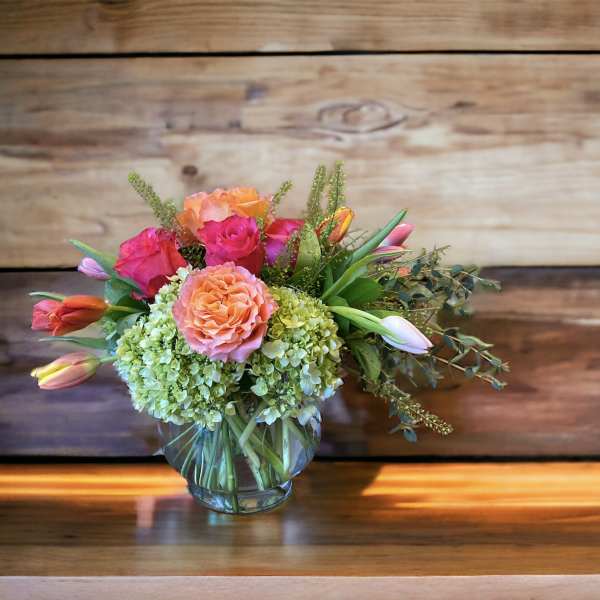 Bouquet of pink and peach roses with tulips in a glass vase