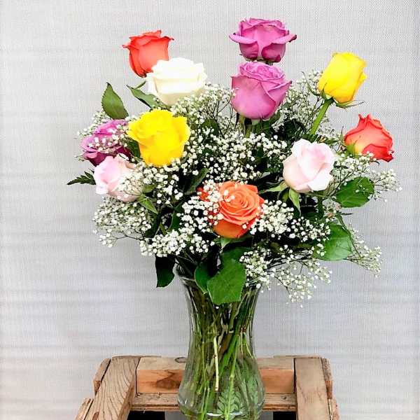 Mixed roses in a clear glass vase with baby's breath.