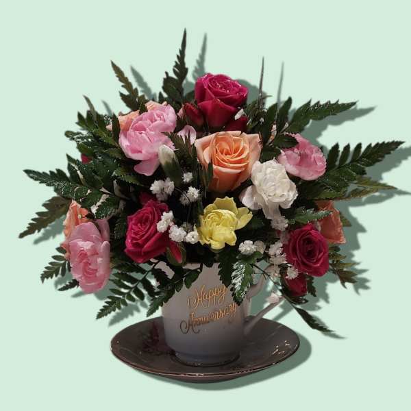 Mixed roses in a teacup vase on a saucer