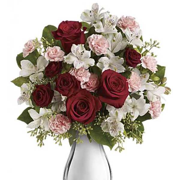 Bouquet of red roses, white lilies, and pink carnations in a glass vase