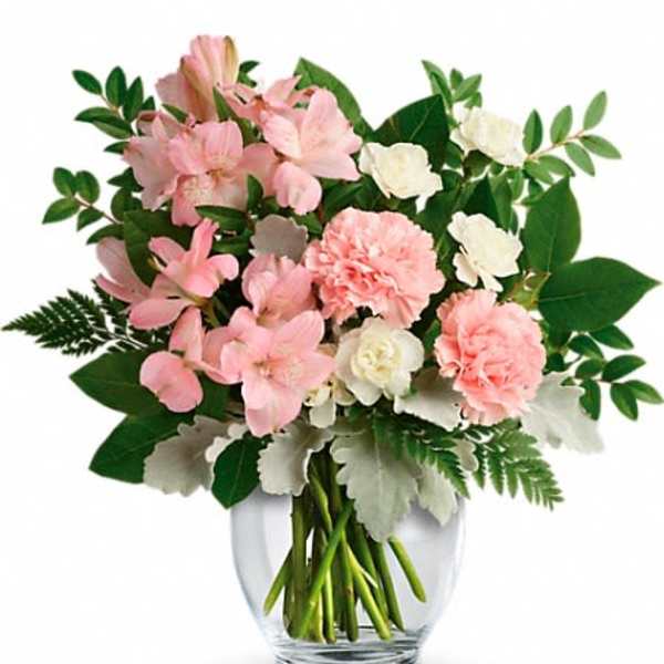 Pink and white flowers arranged in a clear glass vase