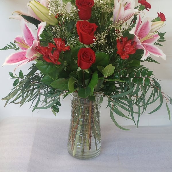 Red roses and pink lilies arranged in a clear glass vase