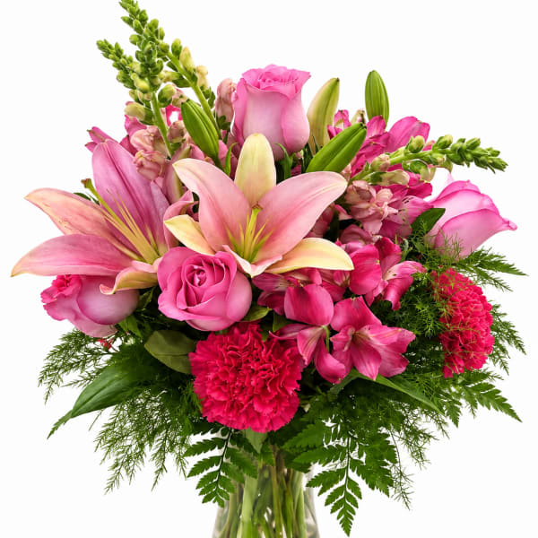 Pink lilies, roses, and carnations in a clear glass vase