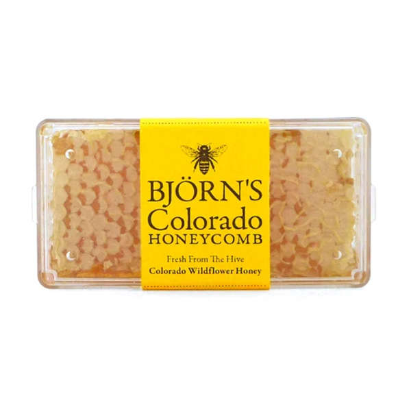 Packaged honeycomb in a clear plastic container with a yellow label
