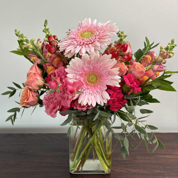 Pink gerbera daisies and mixed pink flowers in a clear glass vase