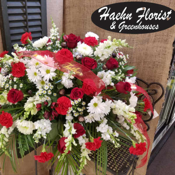 Red and white floral arrangement with roses and daisies in a basket
