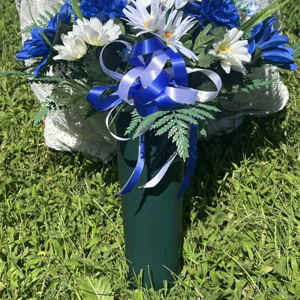Blue and white floral arrangement in a green vase with ribbon
