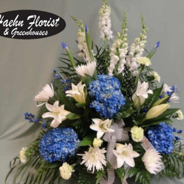 Blue hydrangeas and white lilies in a tall floral arrangement