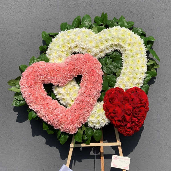 Heart-shaped floral wreaths in pink, white, and red on an easel