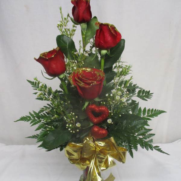 Red roses in a glass vase with a gold bow and glittery heart accents