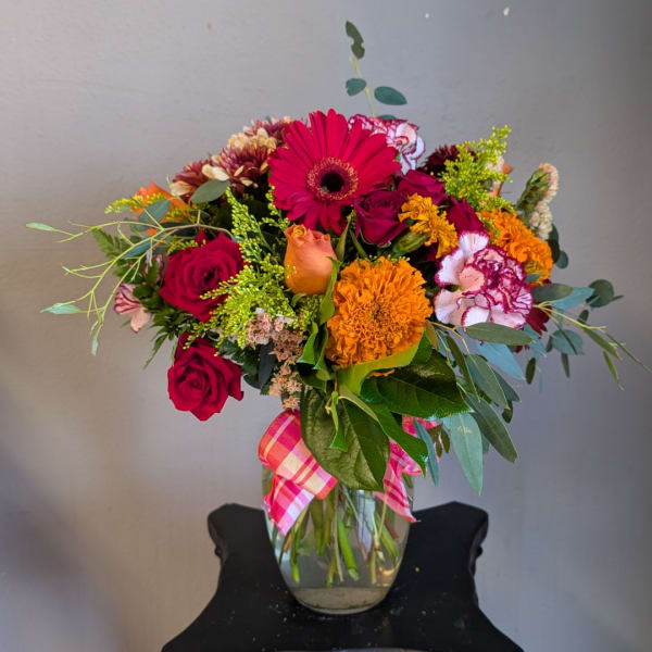 Mixed bouquet of roses, gerbera daisies, and carnations in a glass vase