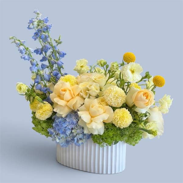 Blue and cream floral arrangement in a white ribbed vase