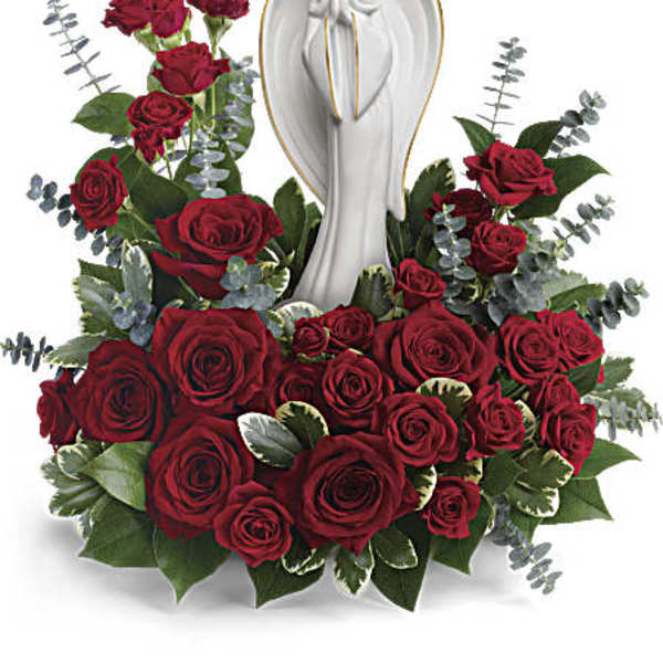 Red roses arranged around a white angel statue