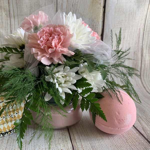 Pink and white flower arrangement with a candle tin and pink bath bomb