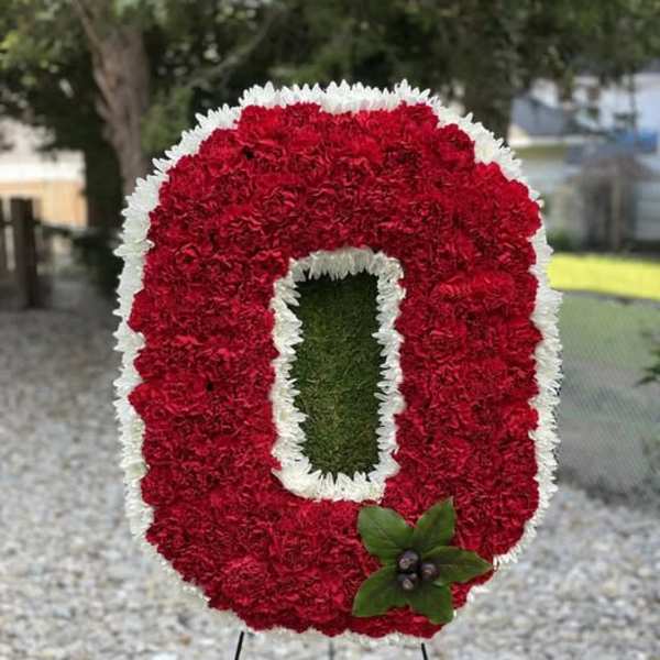 Red and white floral standing tribute shaped like a letter O