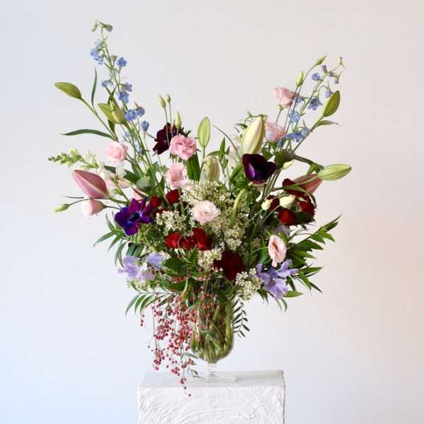 Tall mixed bouquet in a glass vase with pink, red, purple, and blue flowers