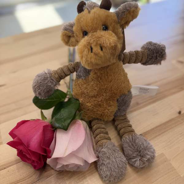 Plush giraffe with two roses on a wooden table
