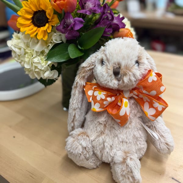 Bouquet with sunflowers, purple flowers, and white hydrangeas beside a plush bunny