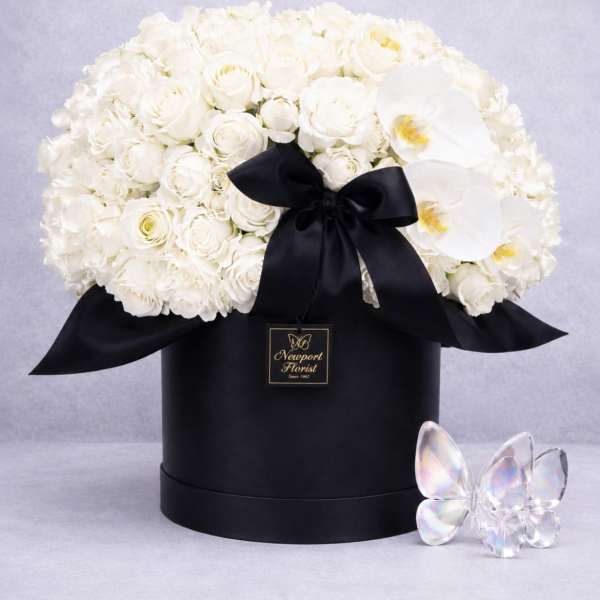 White roses and orchids in a black hat box with a black ribbon