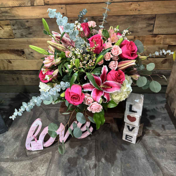 Pink roses and lilies arranged with eucalyptus in a decorative display
