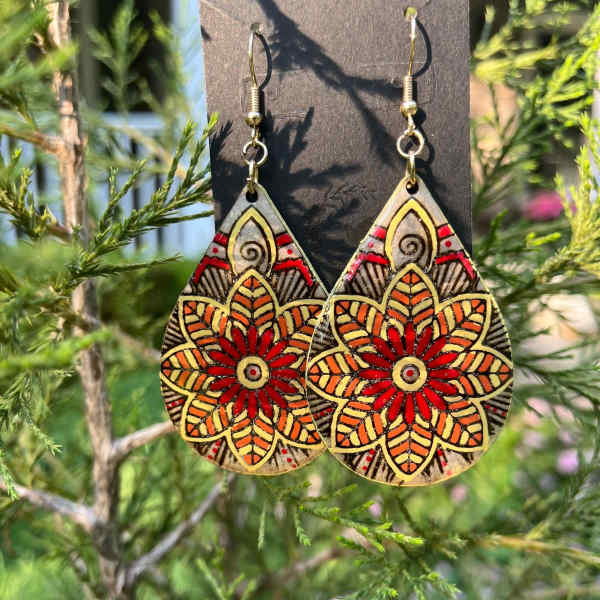 Pair of patterned teardrop earrings hanging outdoors