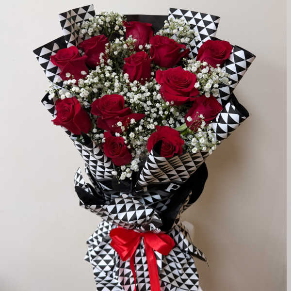 Bouquet of red roses and white baby's breath wrapped in black-and-white patterned paper