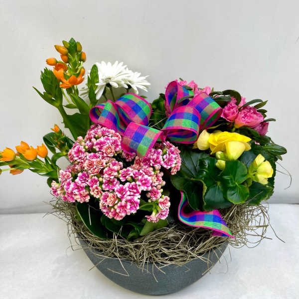 Mixed flower arrangement in a gray bowl with colorful ribbon bows