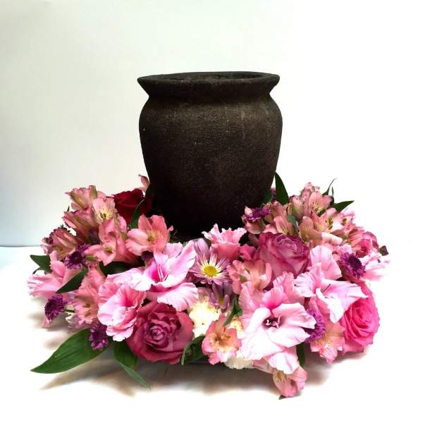 Pink floral arrangement around a dark urn-shaped vase