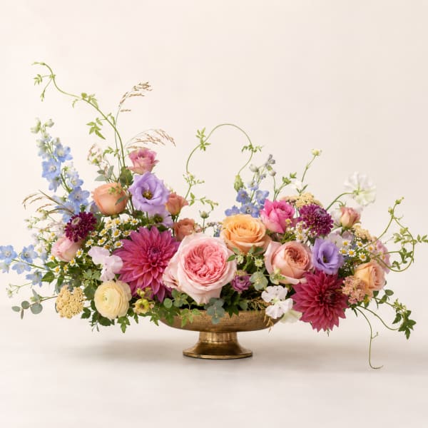 Mixed pastel flower arrangement in a gold pedestal bowl