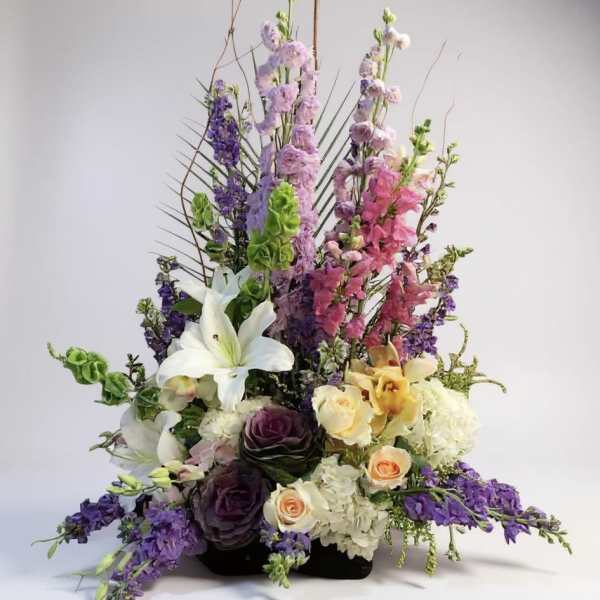 Tall mixed floral arrangement with lilies, roses, and purple blooms
