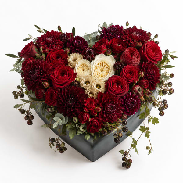 Heart-shaped arrangement of red and cream flowers in a dark box