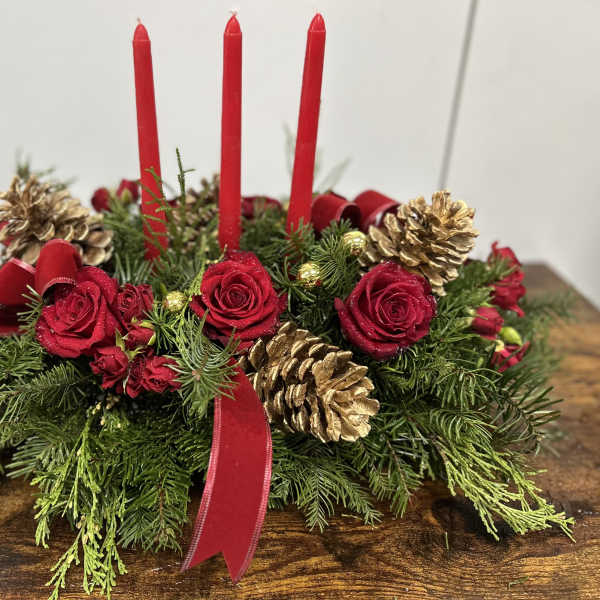 Holiday centerpiece with red candles, red roses, and gold pinecones