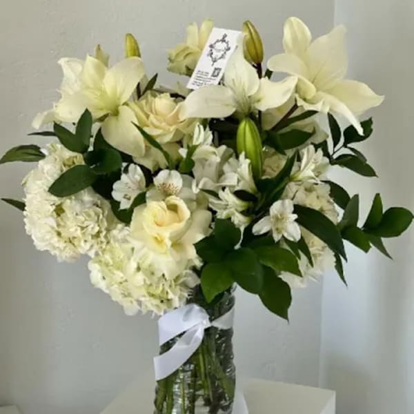 White floral bouquet in a glass vase with a ribbon
