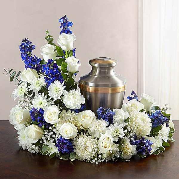 White and blue floral arrangement surrounding a metal urn