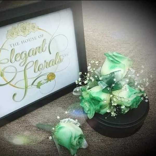 Green rose boutonniere and matching floral display beside a framed sign
