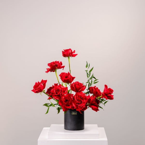 Red roses arranged in a black cylindrical vase